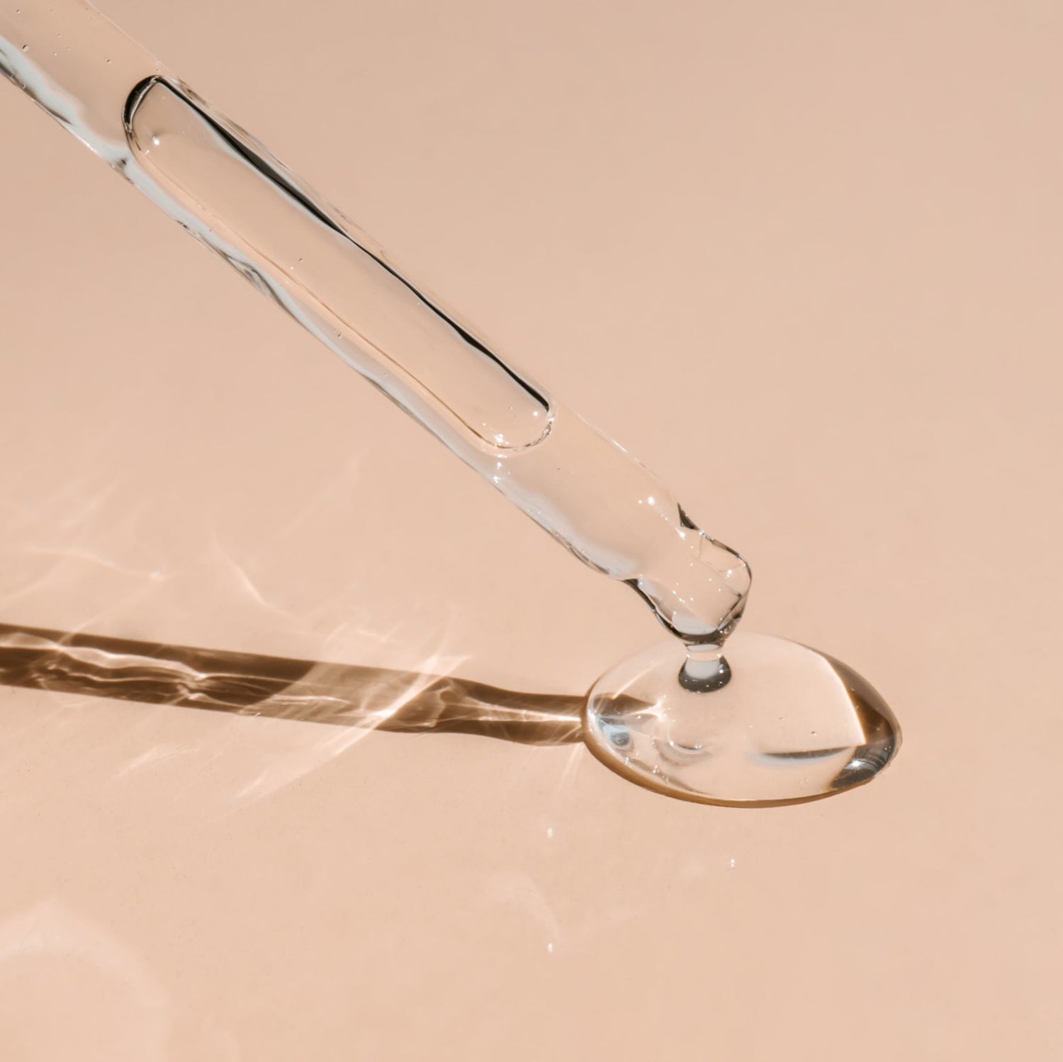 Close-up of a glass dropper with liquid on a beige background