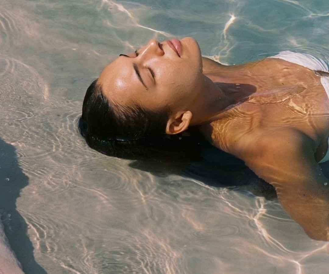 Person lying in clear water with a serene expression